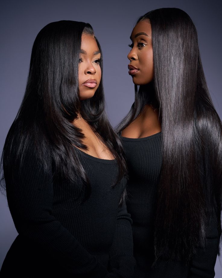 Two models wearing long sleek straight black wigs